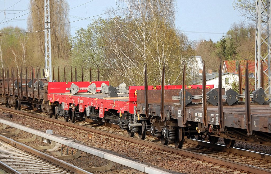 DB CARGO Drehgestellflachwagen mit vier Rads�tzen mit Stirnwandklappen auf diesem Bild ohne Rungen vom Typ Res  6?? in rot in einem amsonsten rein braunf�rbigen Zug, 11.04.11 Berlin-Karow.