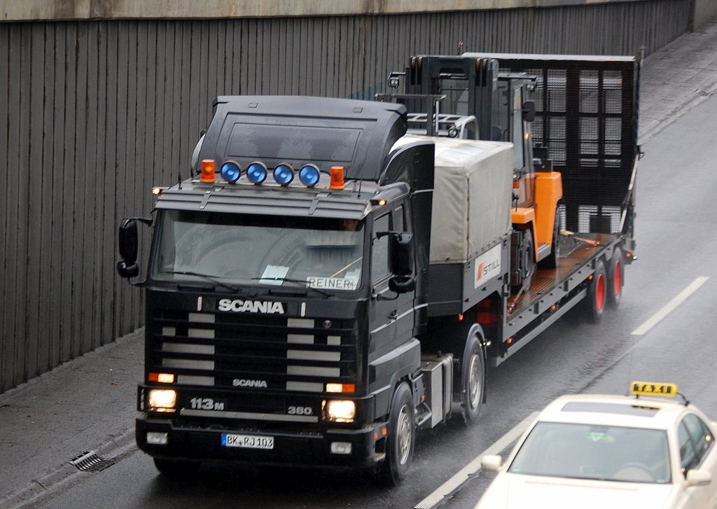 Sieht aus wie neu, diese tolle betagte schwarze SCANIA 113M/380 PS Zugmaschine mit Tiefladeauflieger geh�rt dem Gabelstapler Produzenten STILL, auf der Ladefl�che der gro�e Diesel-Gabelstapler Typ R-70 f�r Lasten von 6,0-8,0 T, 25.01.11 Berliner Stadtautobahn H�he Knobelsdorffbr�cke. 