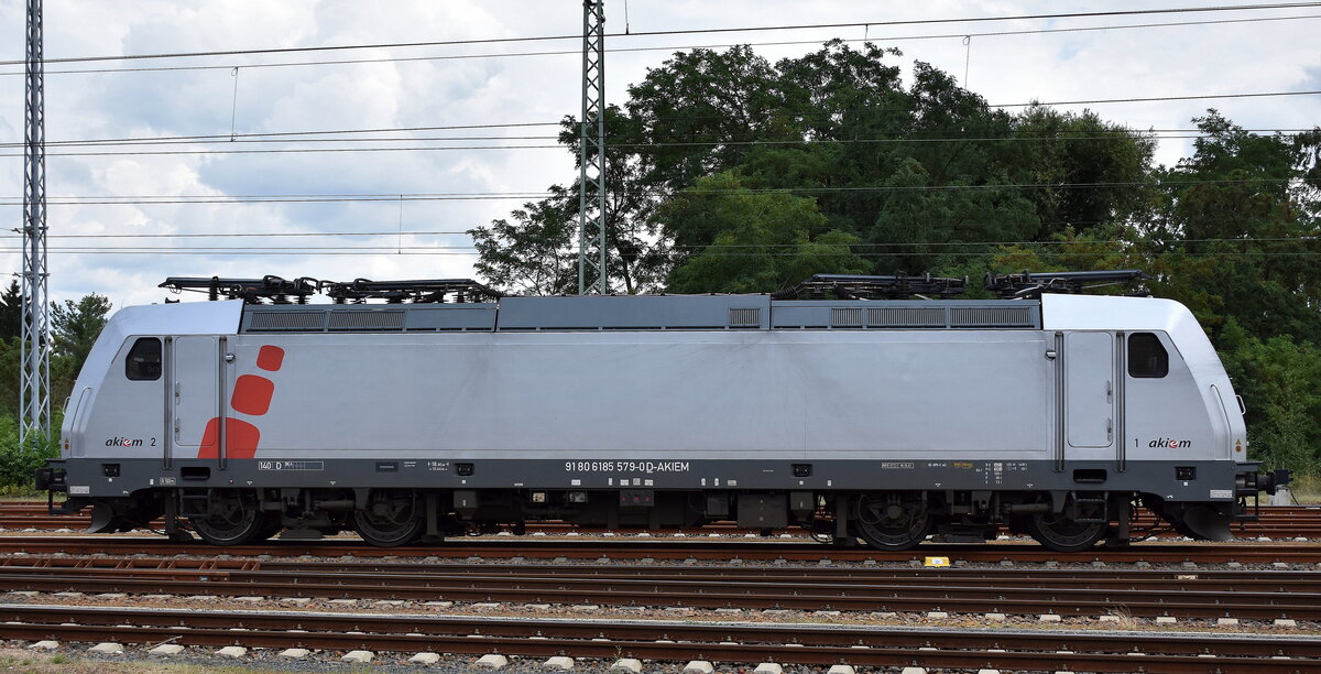 AKIEM SAS, Saint-Ouen [F] Lok  185 579-0  [NVR-Nummer: 91 80 6185 579-0 D-AKIEM], aktueller Leasingnehmer? abgestellt neben einer Abstellgruppe Containertragwagen 30.07.25 Höhe Bahnhof Ruhland.