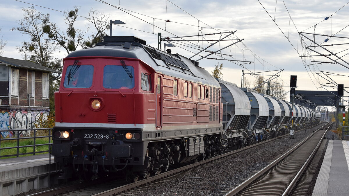 Bahnbetrieb Gera GmbH mit der von der Traktion4Rent GmbH angemieteten Ludmilla  232 529-8  (NVR:  92 80 1232 529-8 D-GERA ) und einigen gedeckten Schüttgutwagen am 04.11.25 Durchfahrt Bahnhof Roßlau (Elbe).