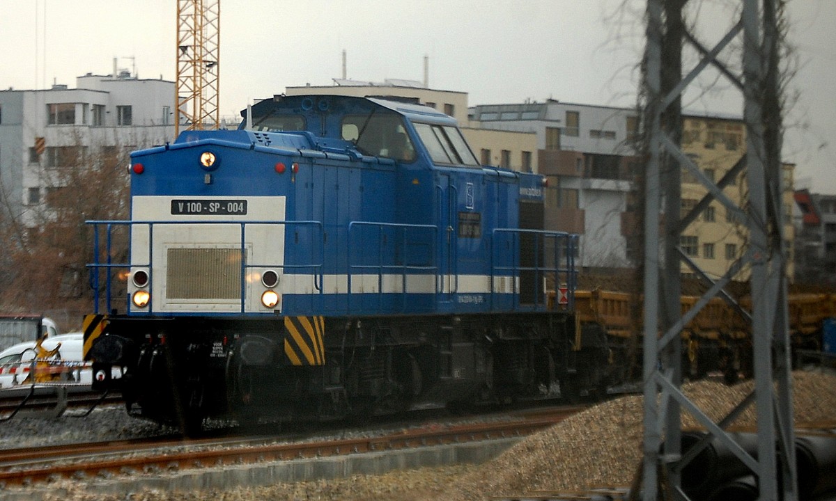 Bild durchs S-Bahnfenster: Die Spitzke Logistik Lok V 100-SP-004  Marielle  (92 84 2203 004-1 NL-SPS) mit meheren Drehgestellflachwagen bei den Gleisarbeiten Nähe S-Bhf. Berlin-Ostkreuz, 18.02.14