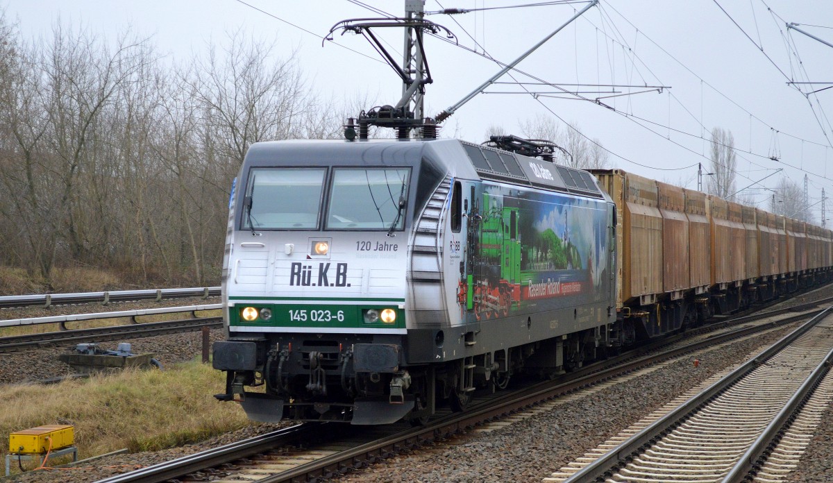Farbtupfer bei grau in grauem Wetter, PRESS 145 023-6 (145 083-2) mit ihrer neuen Folienbeklebung und Holzhackschnitzel-Containerzug Richtung Karower Kreuz Berlin am 21.01.15 Berlin-Hohenschönhausen.
